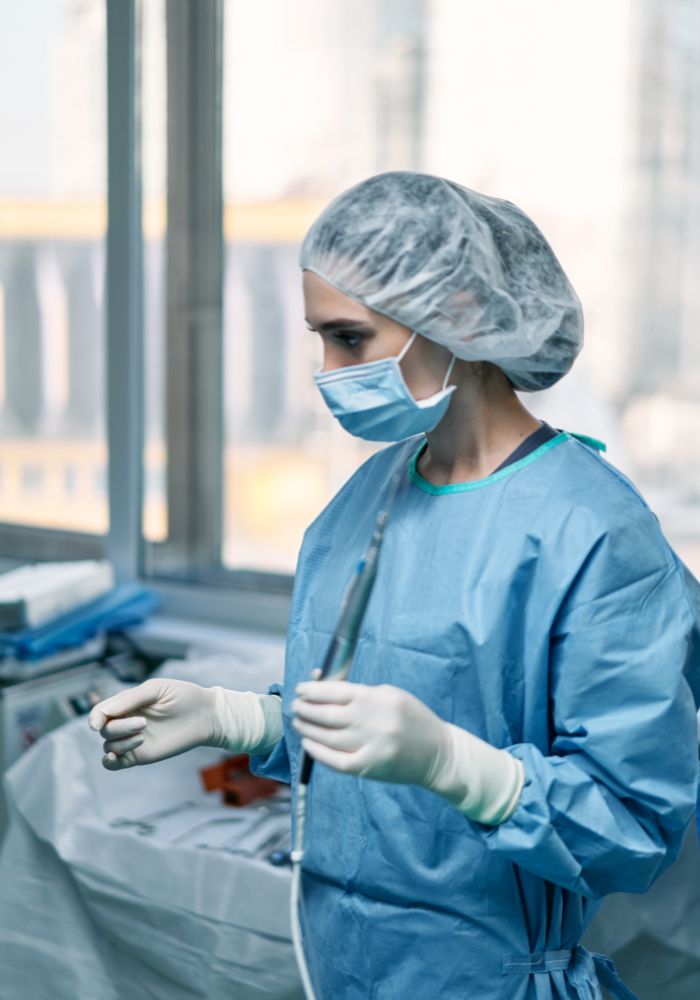 A woman wearing a blue lab coat and a hair net.