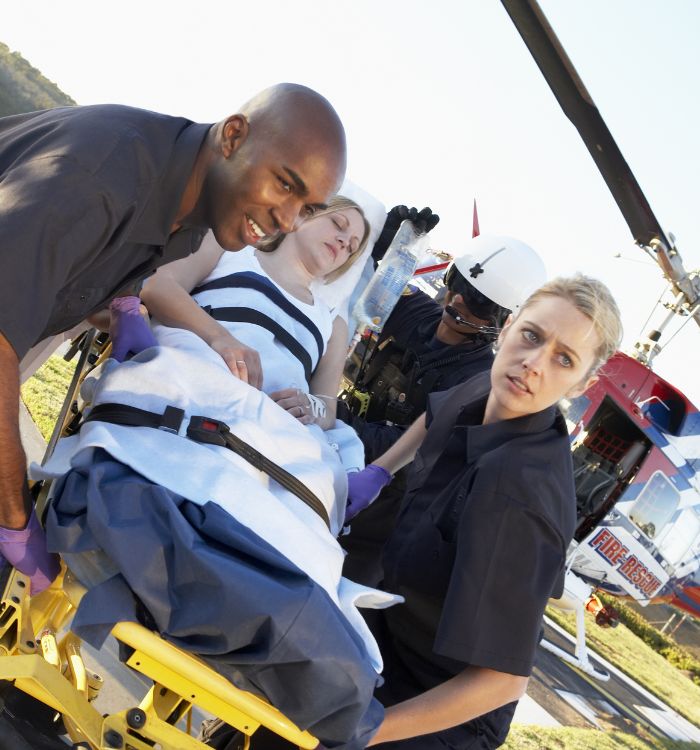 A woman is being lifted onto a helicopter by paramedics.