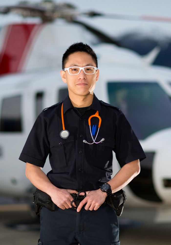 A man wearing glasses and a badge standing in front of a helicopter.