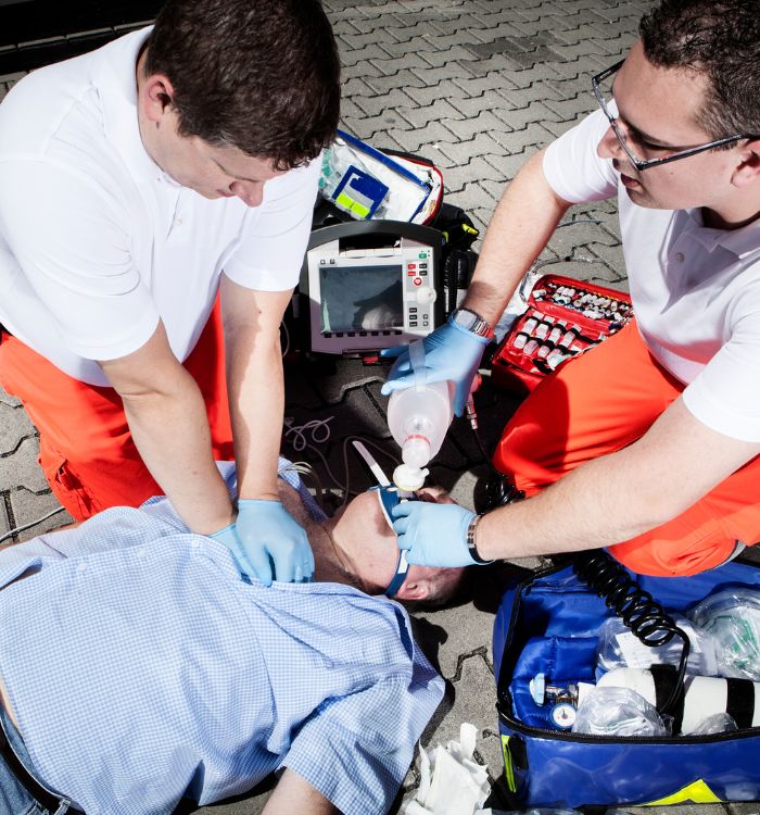 A man is lying on the ground with a medical bag on his chest.