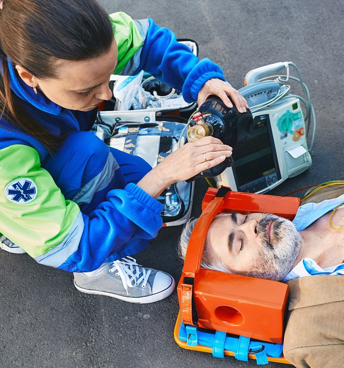 A woman is attending to a man who is lying on the ground.