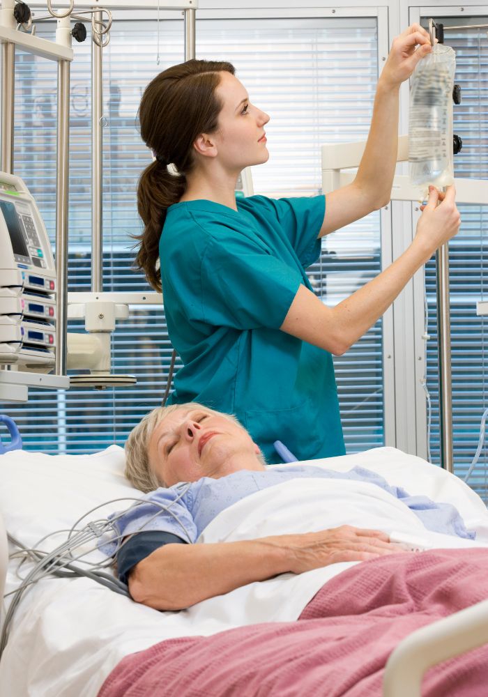 A woman in a blue shirt is holding a bag of saline solution.
