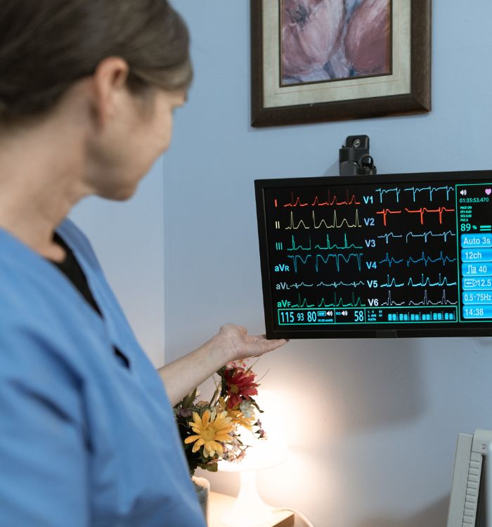 A woman in a blue shirt is holding a monitor that shows a heart rate.