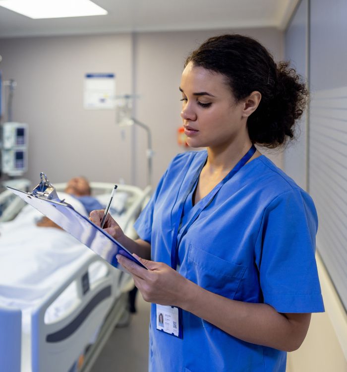 A woman in a blue shirt is writing on a clipboard.