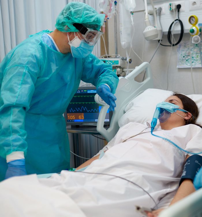 A man in a green suit is helping a woman on a hospital bed.