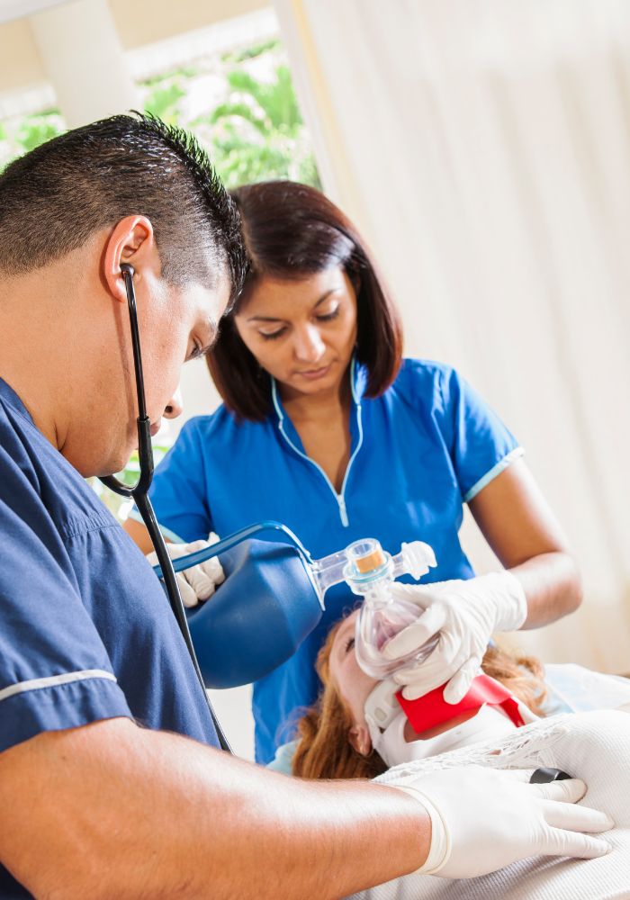 A man in a blue shirt is giving a woman a breathing treatment.