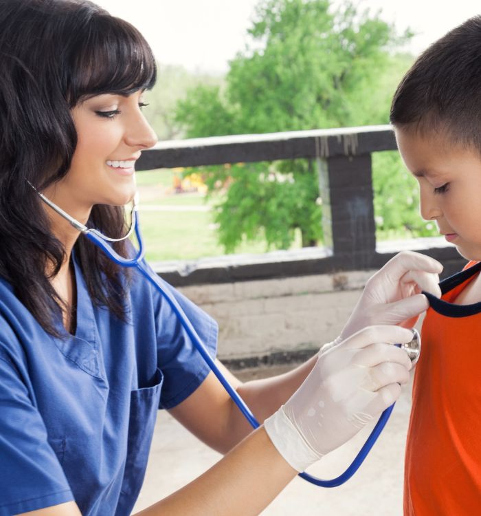 A woman in a blue shirt is taking a boy's heart rate.