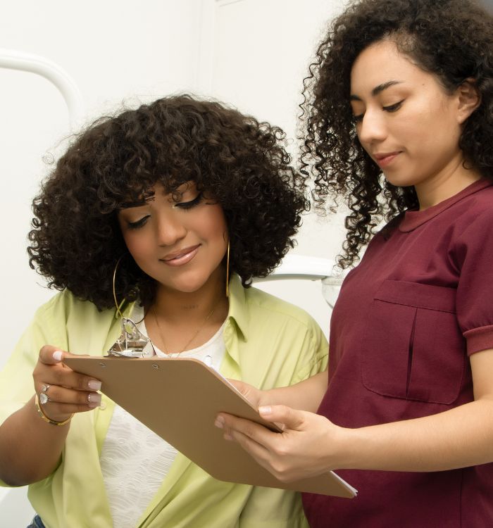 Two women looking at a clipboard, one of them is a nurse.