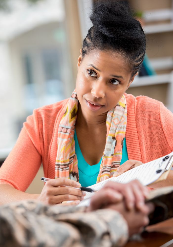 A woman writing in a book with a colorful scarf around her neck.