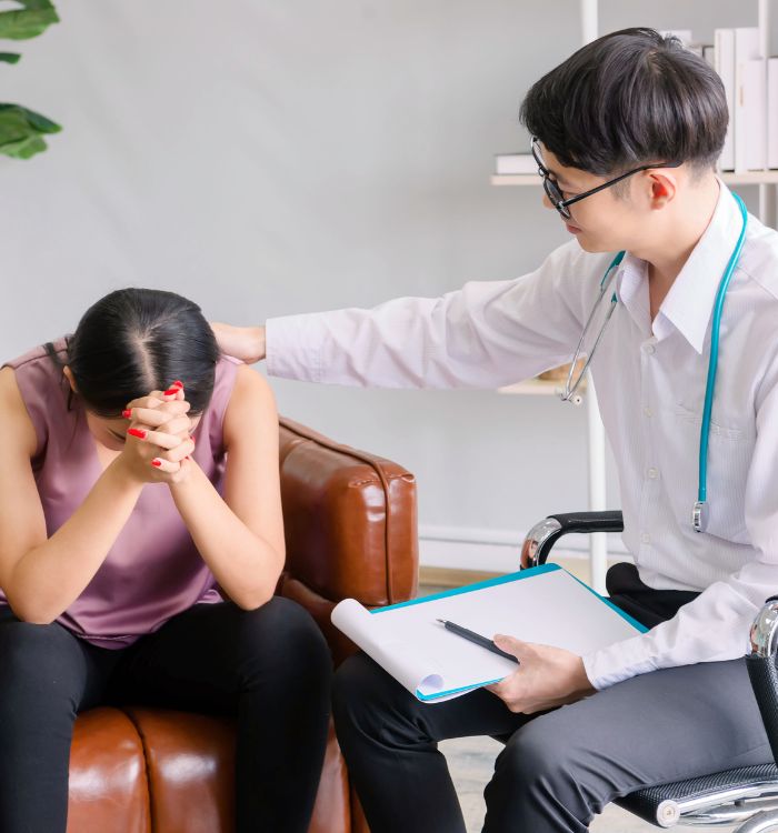 A man in a white shirt and a stethoscope is talking to a woman.