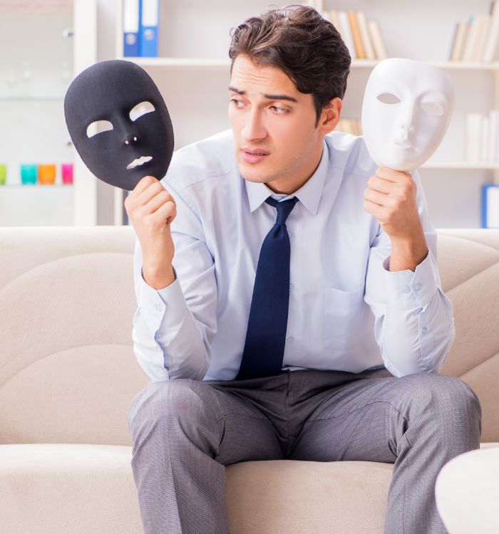 A man wearing a blue shirt and tie holding a black and white mask.