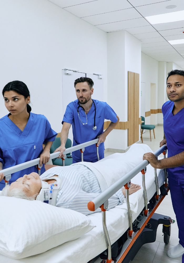 A woman in a hospital bed with a medical team standing around her.