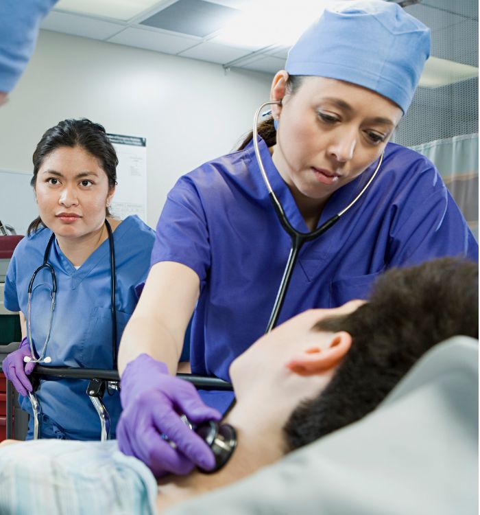 A woman in a blue uniform is examining a patient.