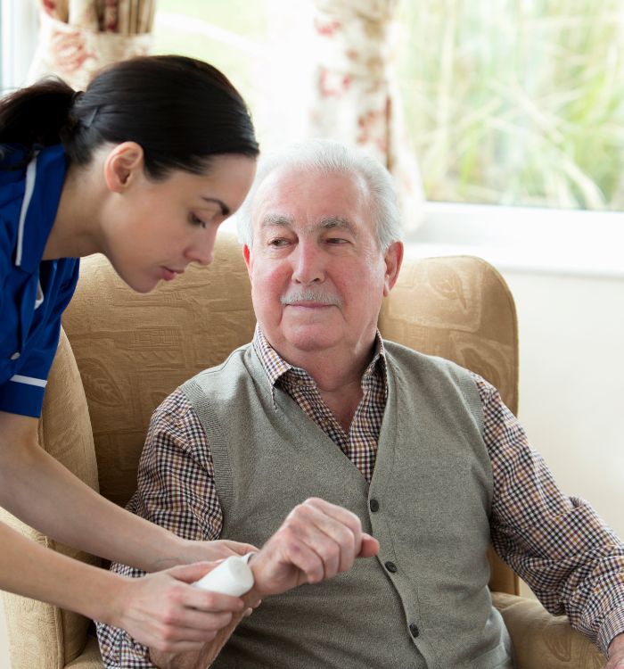 A woman in a blue shirt is helping an older man with a white beard.