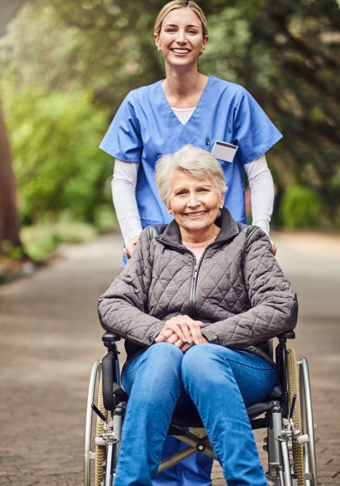 A woman in a wheelchair is smiling at a nurse.