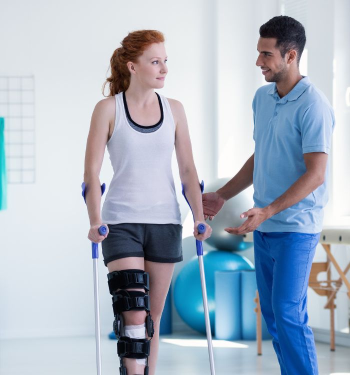 A woman with a broken leg and a man in a blue shirt talking to her.