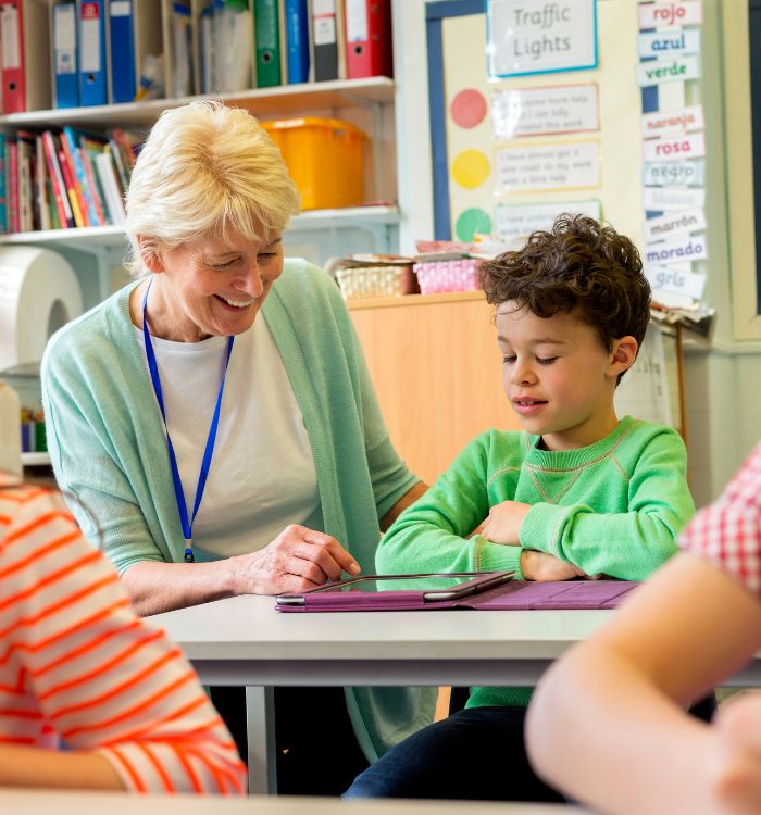 A woman and a boy sitting at a table with a laptop.