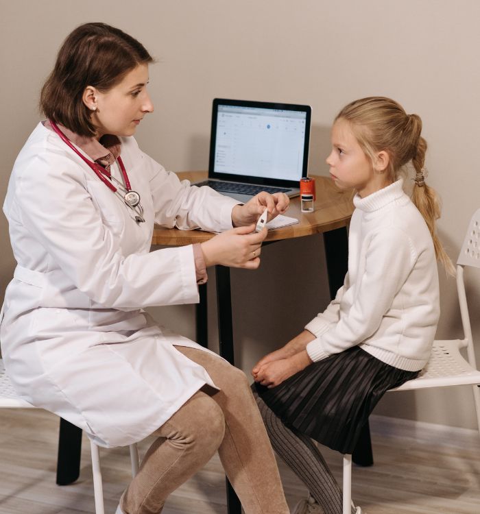 A woman in a white coat is treating a young girl.