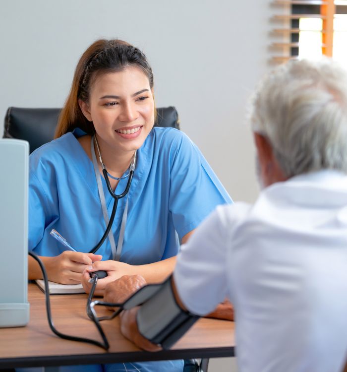 A woman wearing a blue shirt and a stethoscope is smiling at a man.