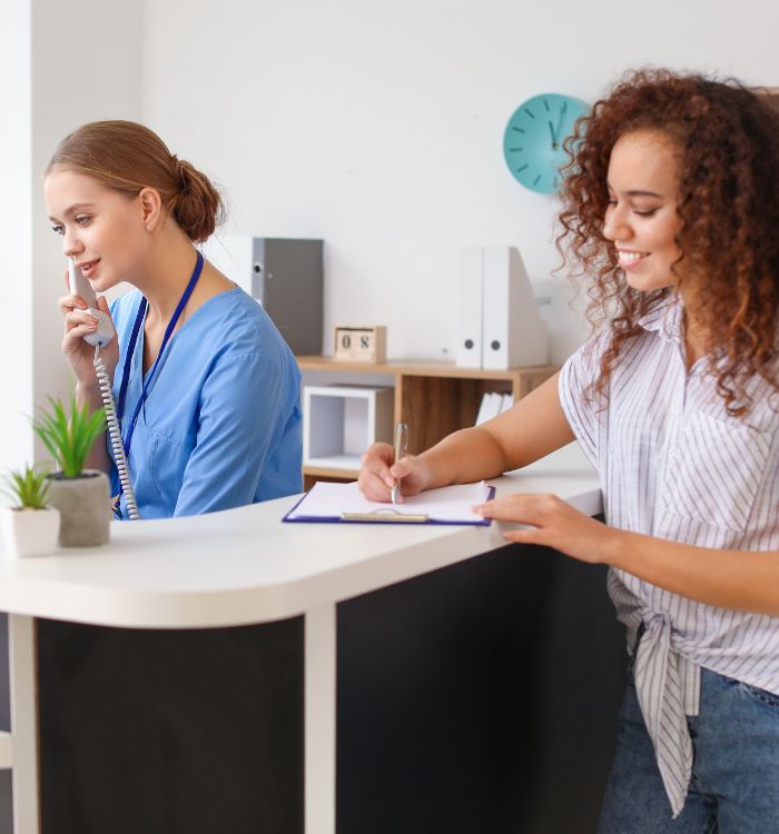 A woman in a blue shirt is writing in a notebook.