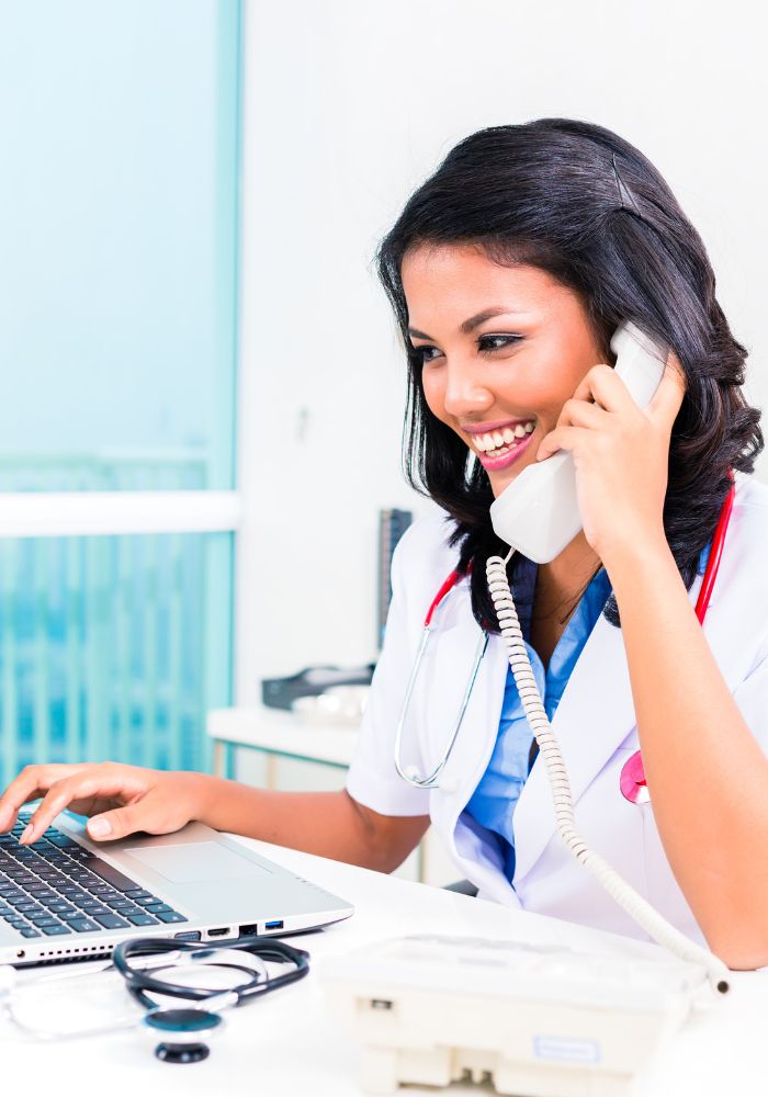 A woman wearing a white coat is talking on a phone.