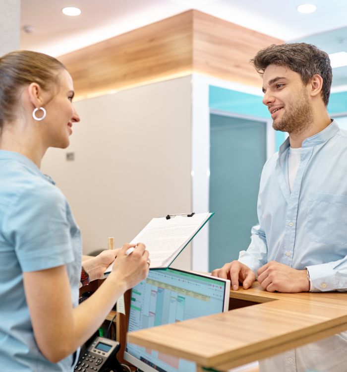 A woman in a blue shirt is talking to a man at a desk.