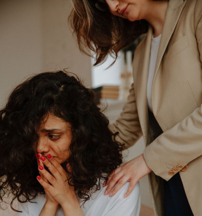 A woman with a ponytail and red nails is being touched by another woman.