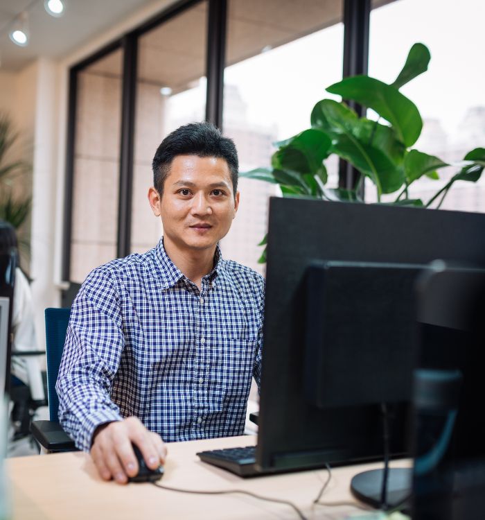 A man sitting in front of a computer with a mouse in his hand.