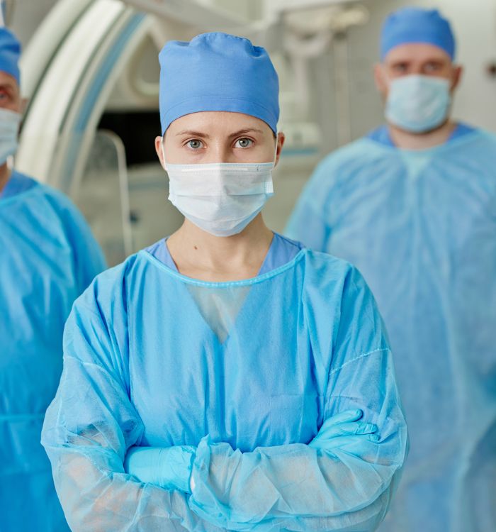 A woman in a blue scrub suit with a mask on her face.