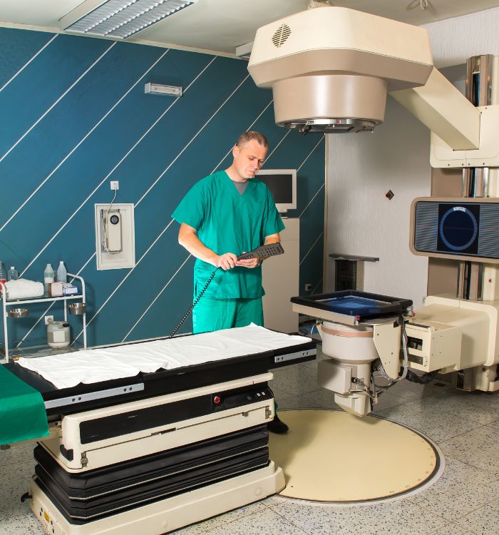 A man in a green shirt is standing in front of a medical machine.