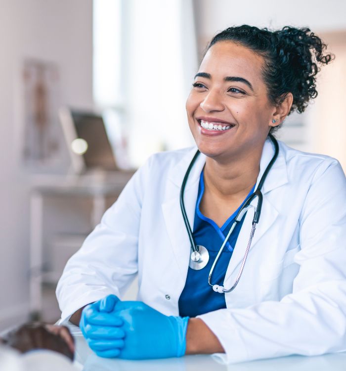 A woman wearing a white coat and blue gloves.