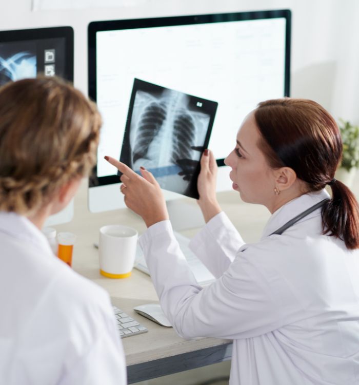 Two women in white lab coats are looking at a medical image..