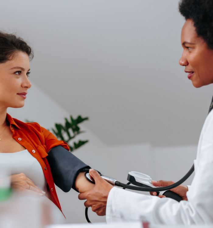 A woman wearing a red shirt is getting her blood pressure checked.