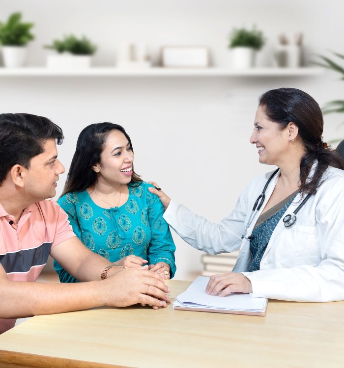 A woman in a white coat is talking to a man and a woman.