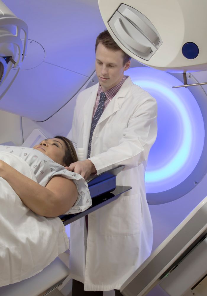 A man in a white lab coat is standing next to a woman who is lying on a table.