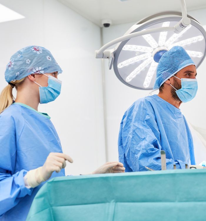 A man and woman in blue scrubs are working on a patient.