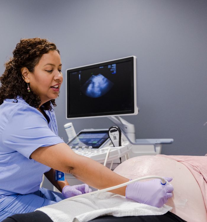 A woman in a blue shirt is attending to a patient.