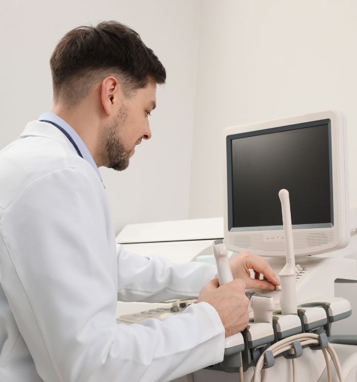 A man in a white lab coat is working with a computer.