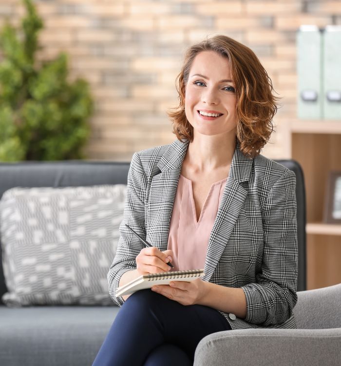 A woman wearing a suit and writing in a notebook.