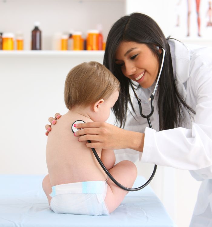 A woman in a white lab coat is examining a baby.