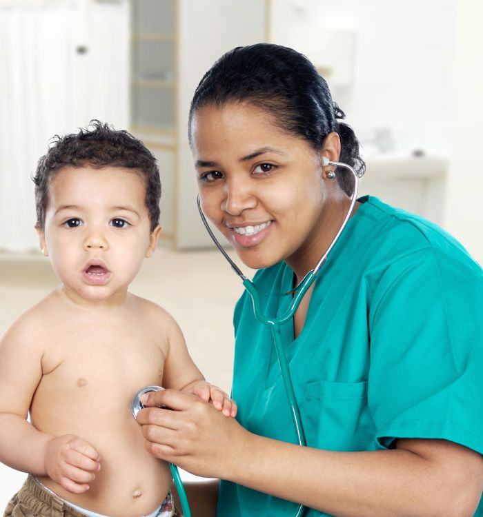A woman in a green shirt is showing a baby her stethoscope.