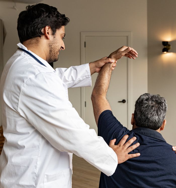 A man in a white coat is massaging another man's back.