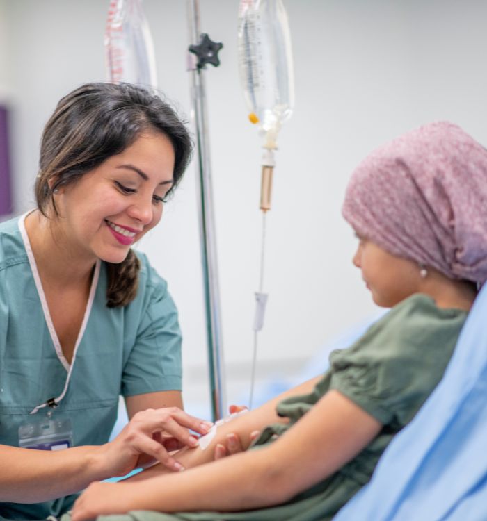 A woman in a green shirt is tending to a child in a hospital bed.