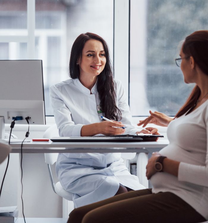 A woman in a white lab coat sitting at a desk.