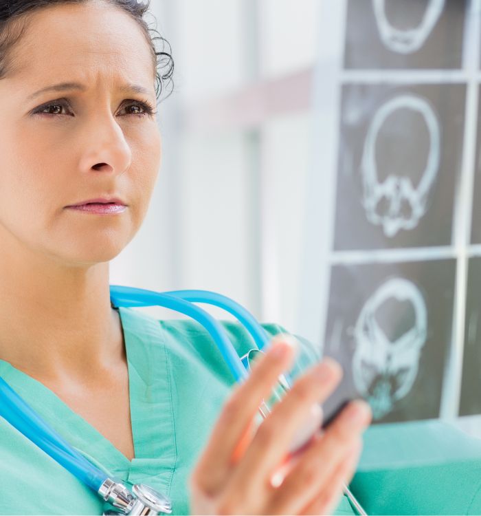 A woman in a green shirt and a stethoscope is pointing at a picture of a brain.