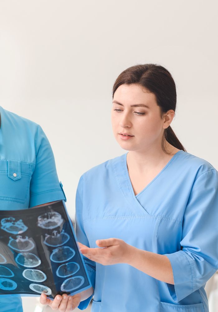 A woman in a blue shirt is holding a picture of a brain.