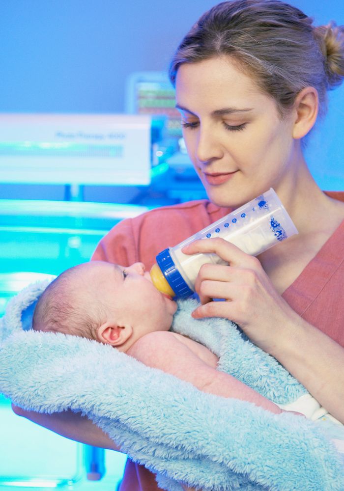 A woman is feeding a baby with a bottle.