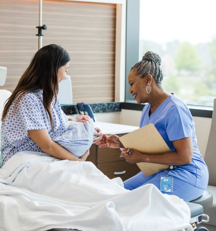 A woman in a hospital bed with a nurse.