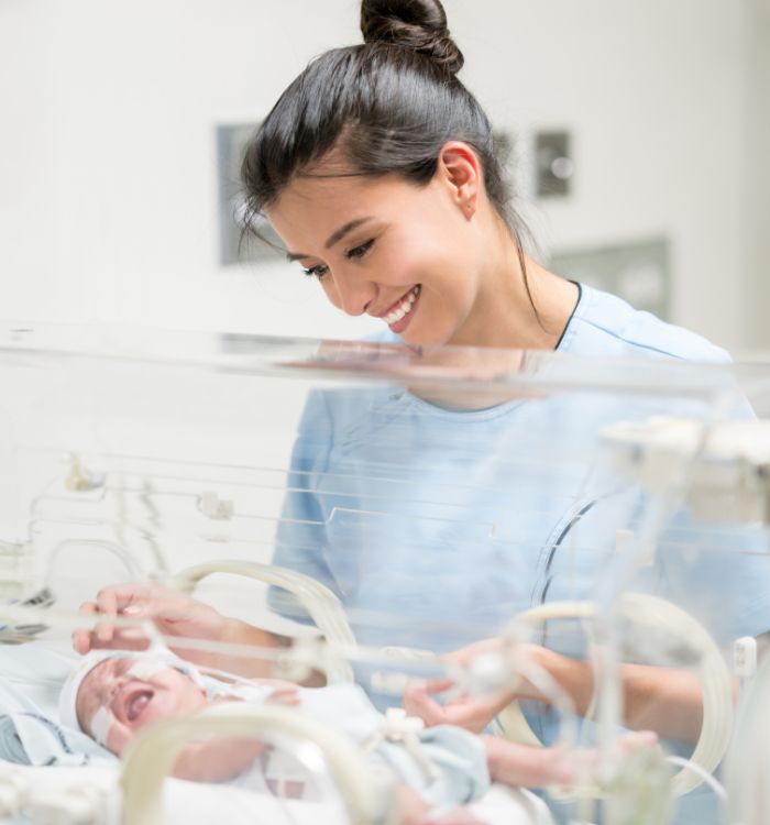 A woman smiling at a baby in a hospital.