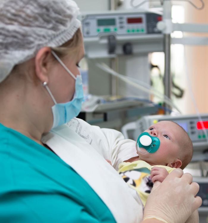 A woman holding a baby with a pacifier.